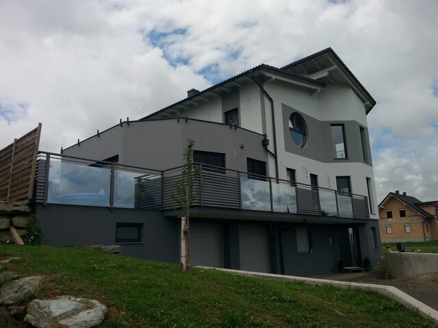 Mehrstöckiges Wohnhaus mit umlaufenden Metallbalkonen im Grünen
