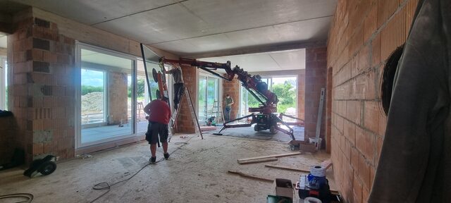 Minikran hebt ein rundes Dachelement über einem Gartenhaus ein