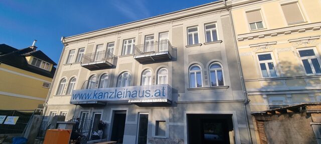 Fassade eines Mehrfamilienhauses mit Glasbalkonen im Straßenzug