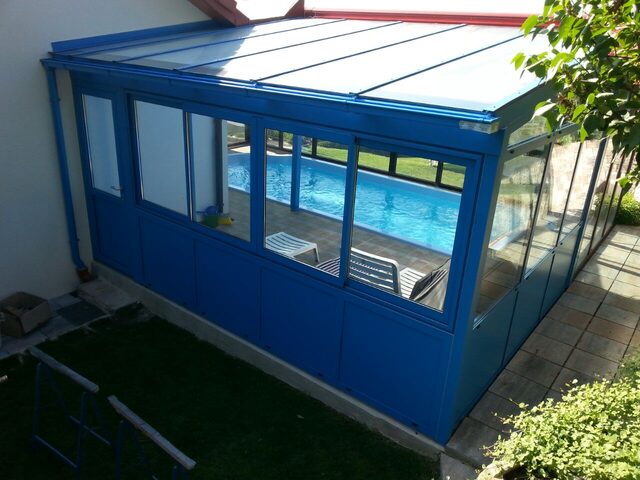 Blau lackierte Poolüberdachung aus Metall und Glas mit Schiebeelementen