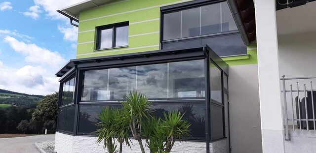 Verglaster Wintergartenanbau mit Metallrahmen an einer Hausfassade