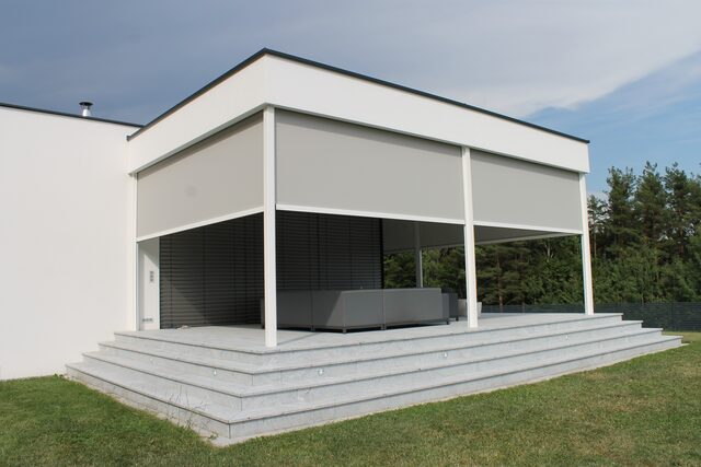 Terrassenüberdachung mit ausfahrbaren Sonnenschutz-Screens an einem modernen Flachdachhaus