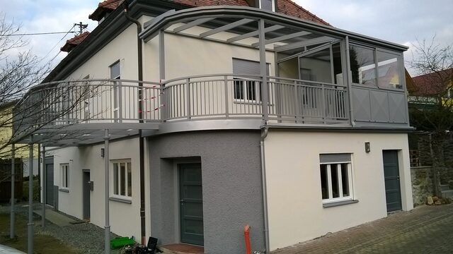 Geschwungene Balkon- und Terrassenüberdachung mit Glasdach an einem Altbau